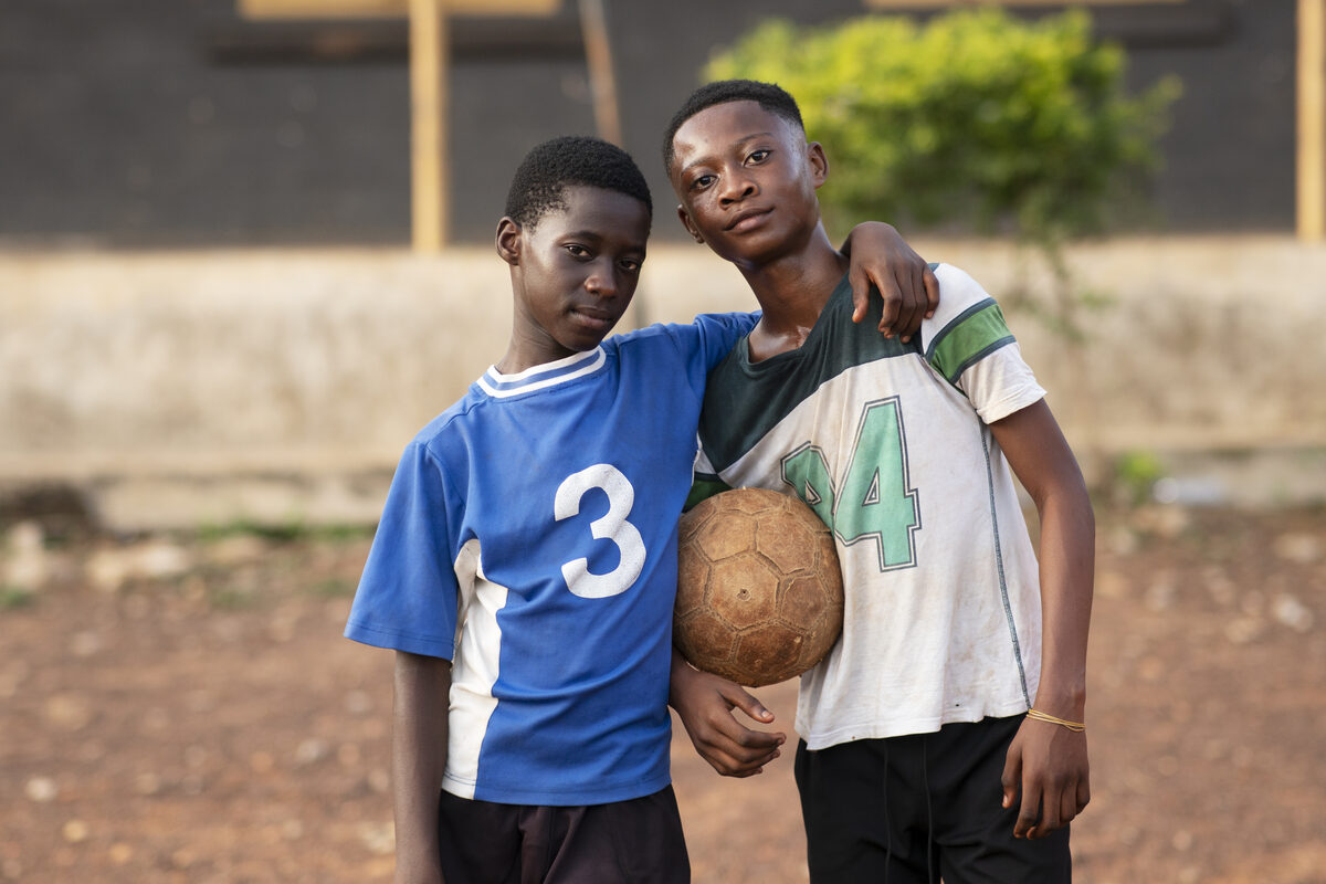 Two young African footballers with a ball on a community pitch